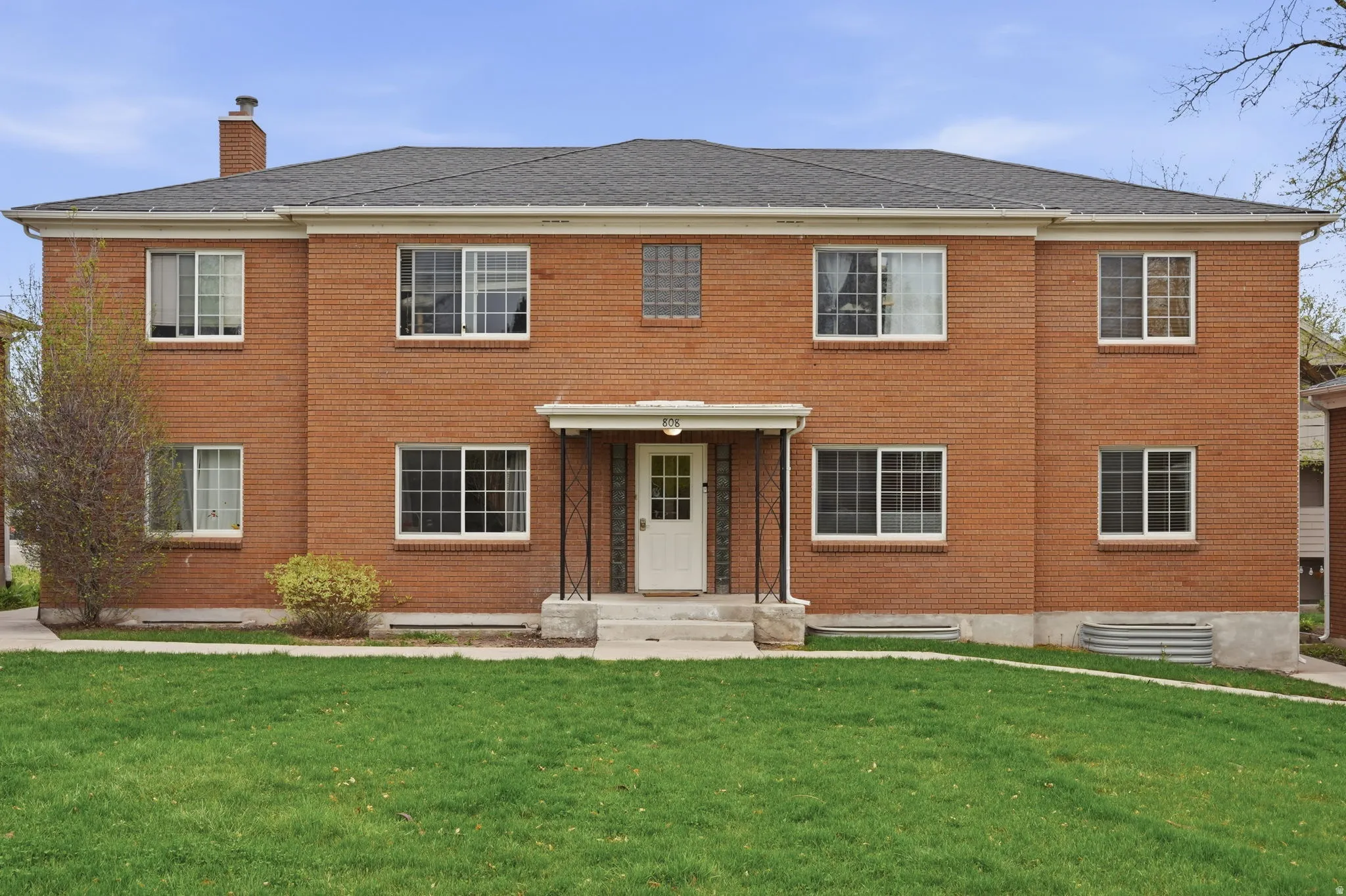 Colonial home featuring brick siding, a front yard, and a chimney