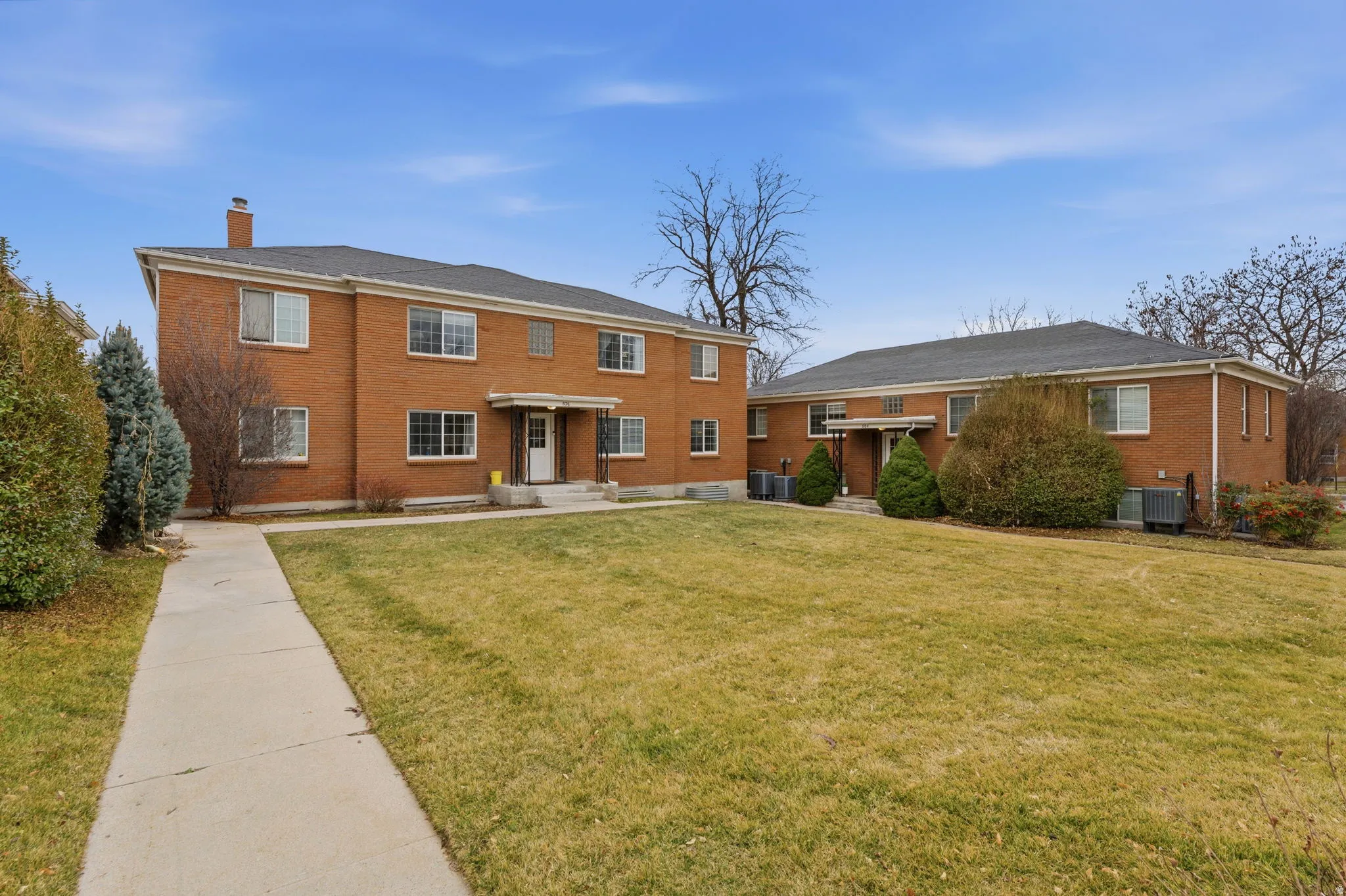 Back of house featuring a chimney, brick siding, and a lawn