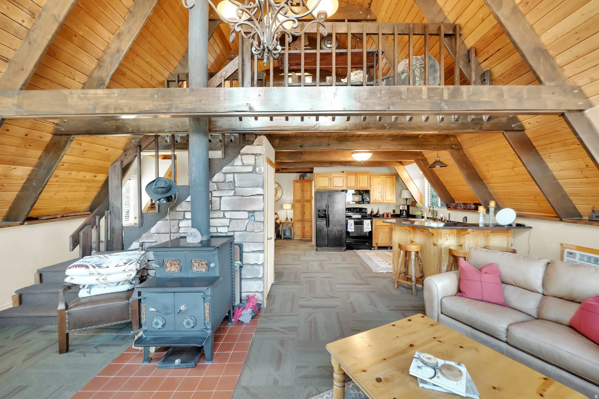 Living room with a high wooden beamed ceiling, a wood stove, light carpet, a chandelier, and plenty of natural light