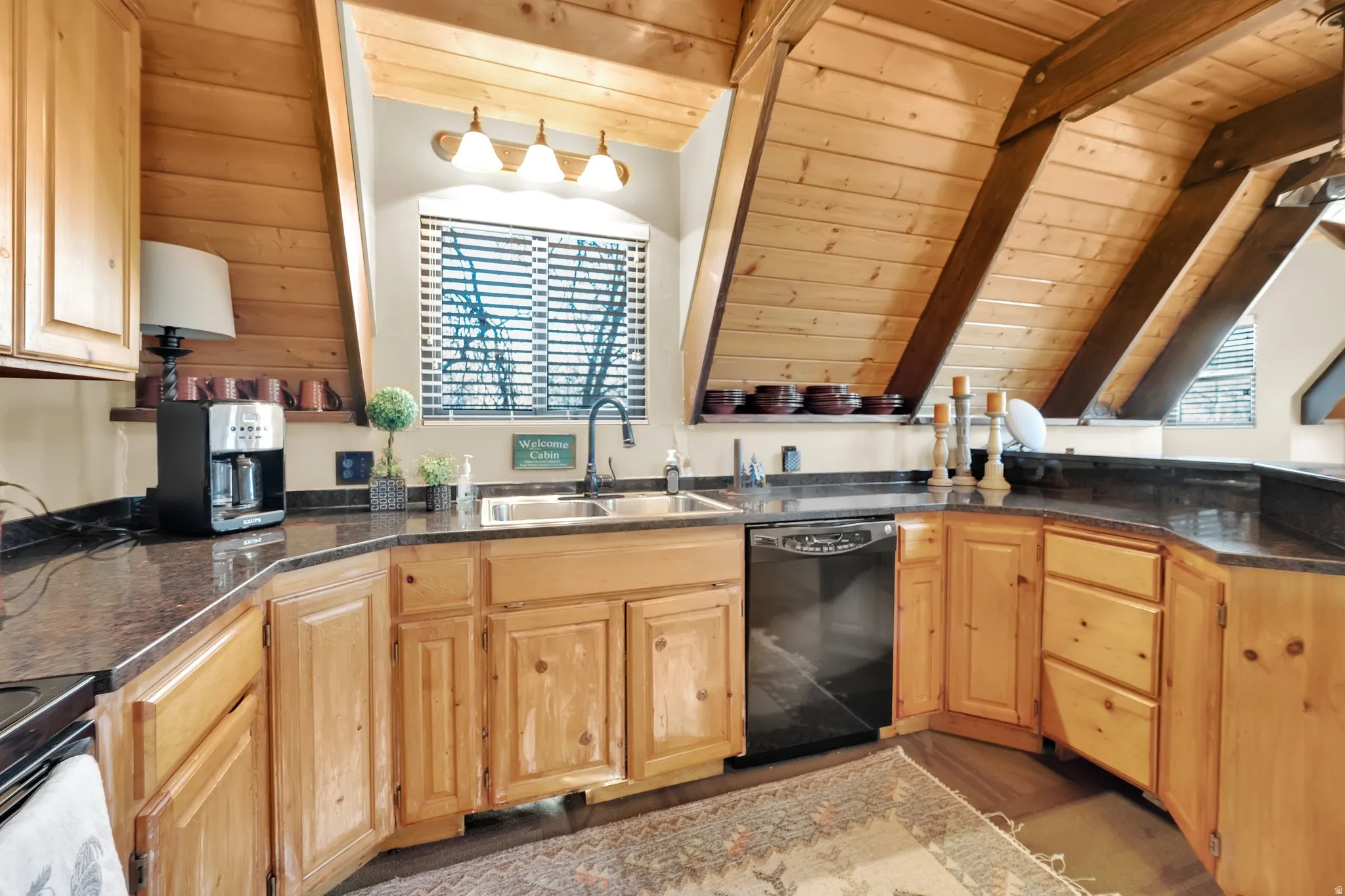 Kitchen with wood ceiling, black appliances, light wood finish cabinets, and vaulted ceiling with beams