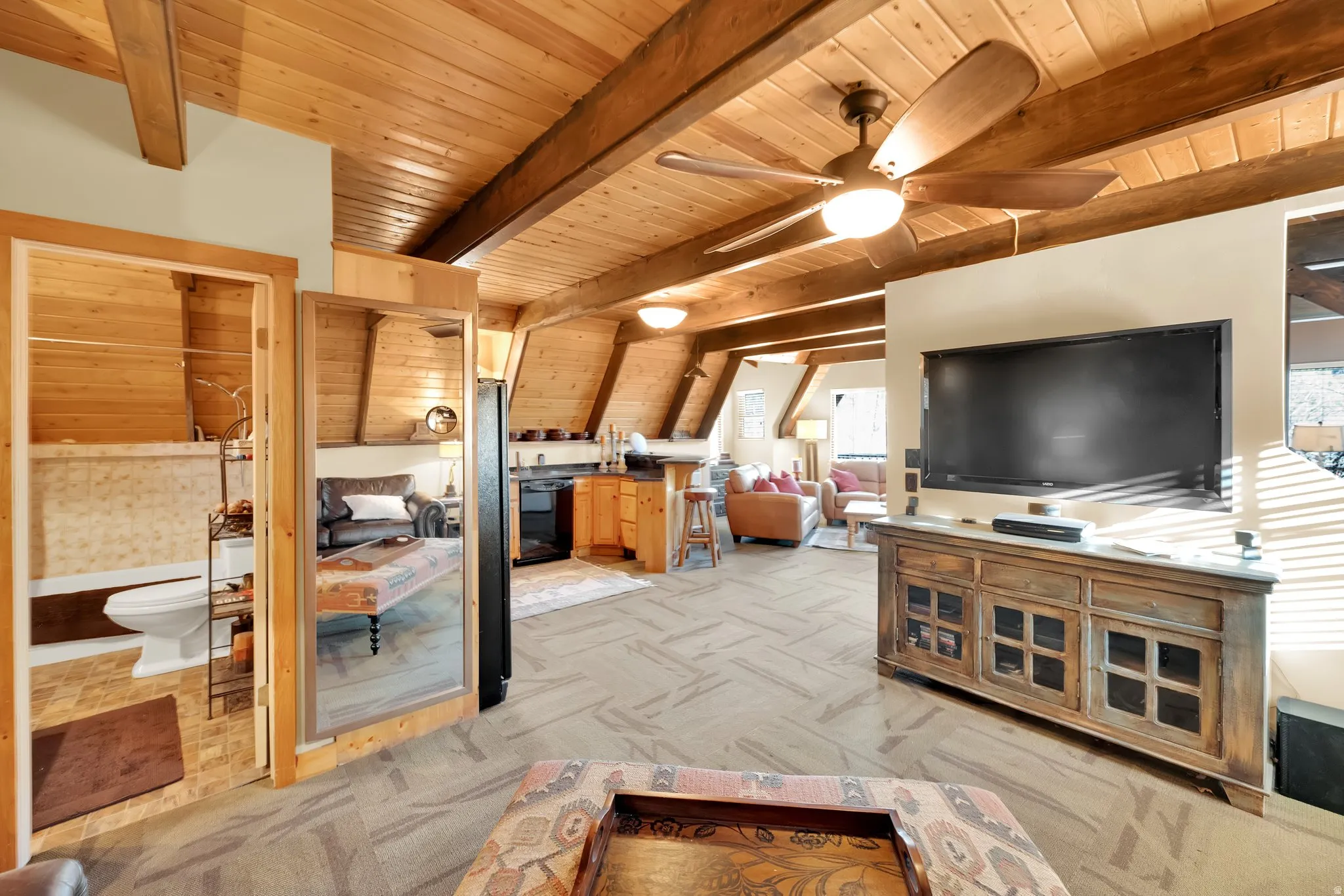 Living area with light carpet, a wood ceiling with exposed beams, and ceiling fan