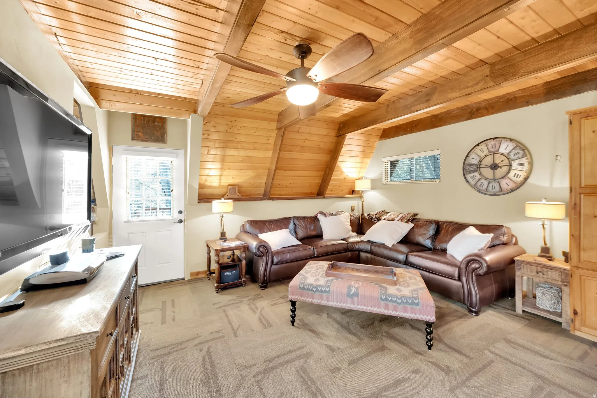 Living room featuring a wooden ceiling with exposed beams, ceiling fan, and light carpet
