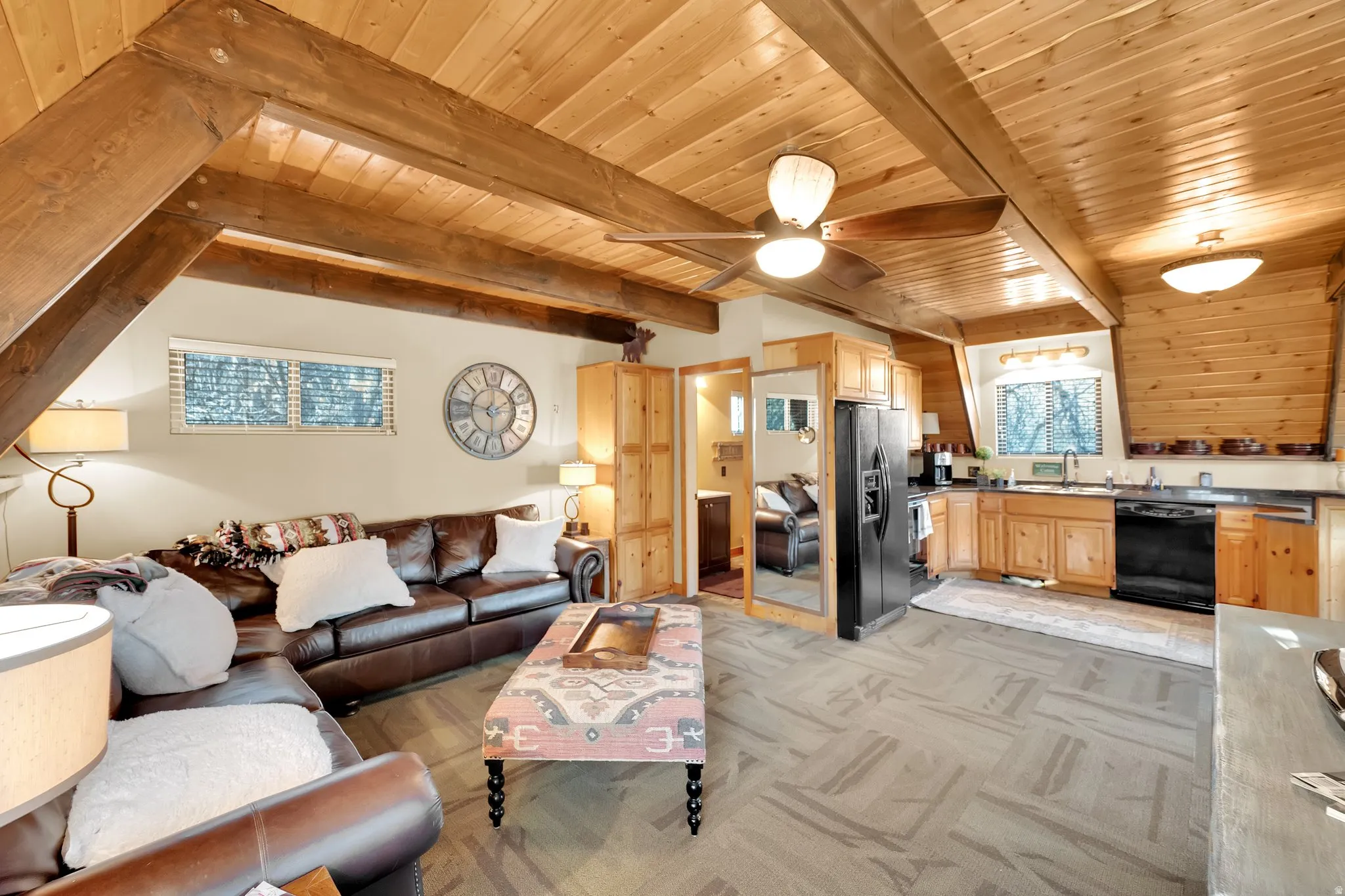 Living area featuring a wooden ceiling with exposed beams, light colored carpet, and ceiling fan