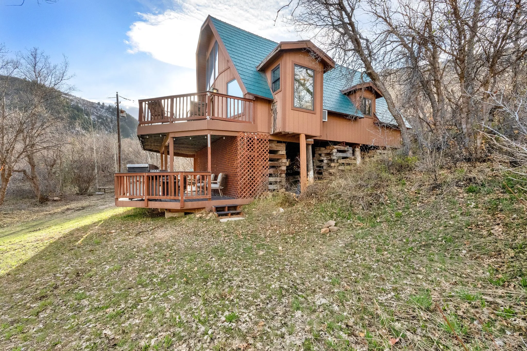 Back of property featuring a deck with mountain view and a lawn