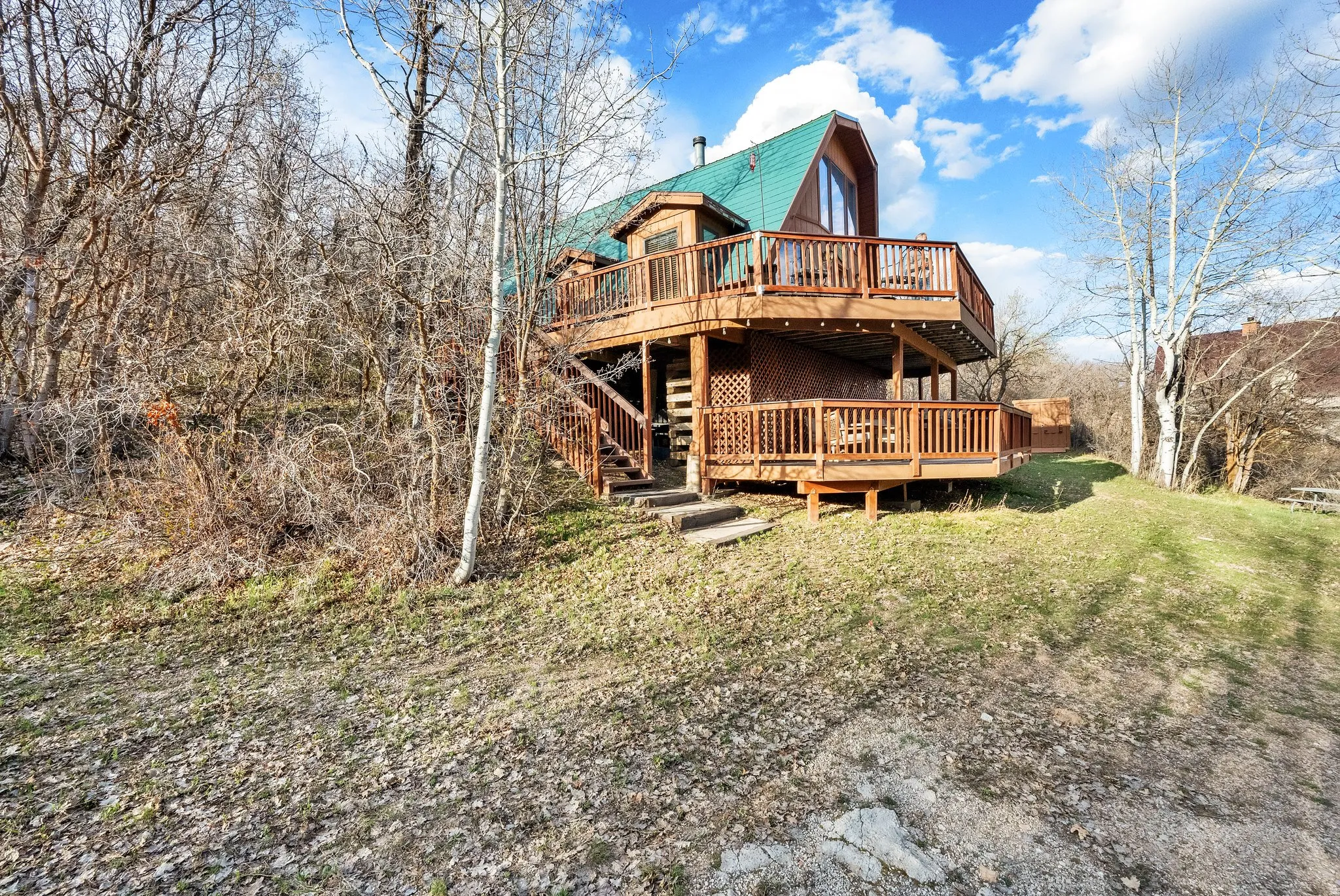 Rear view of property featuring a deck, a gambrel roof, and a yard