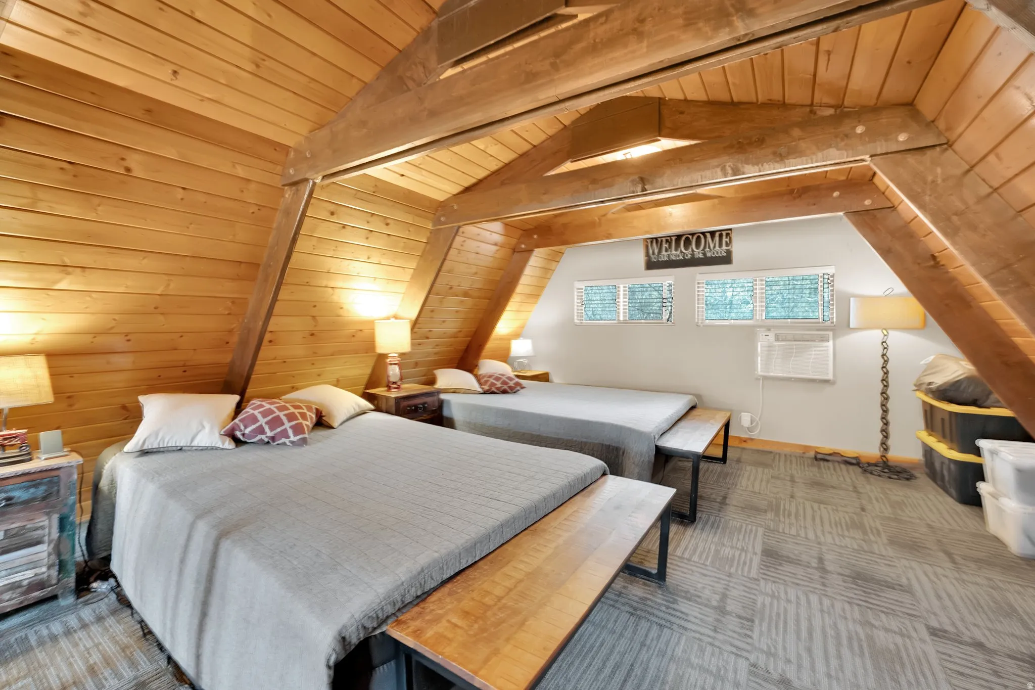 Carpeted bedroom with a wooden ceiling with exposed beams and wooden walls
