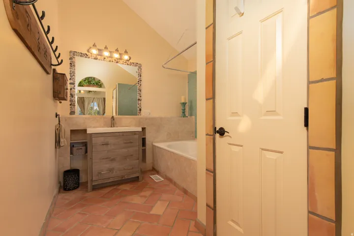 Full bathroom with vaulted ceiling, vanity, and tiled shower / bath