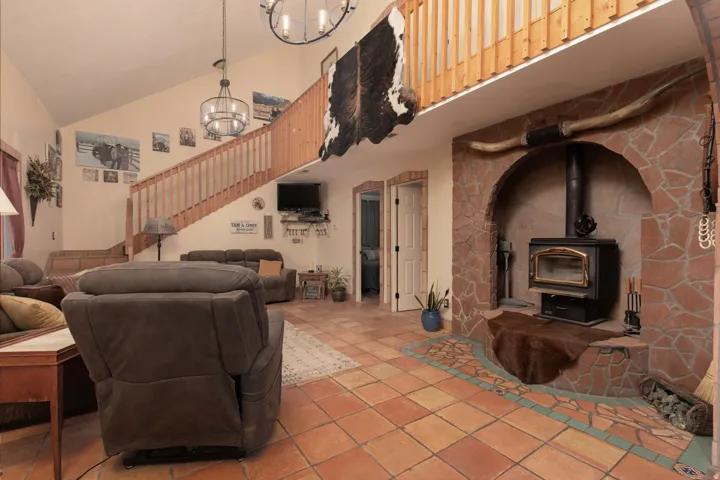 Tiled living area with a wood stove, hanging lights, and vaulted ceiling