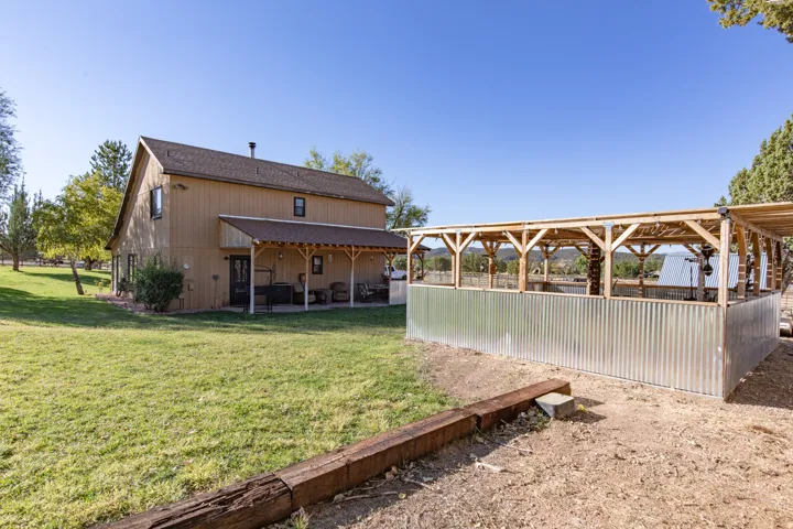 Back of house featuring a patio area, a yard, and a shingled roof