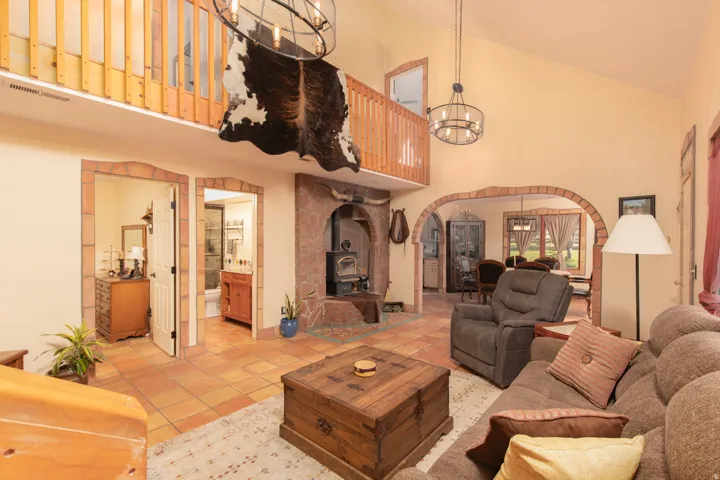 Living room with arched walkways, suspended lighting, lofted ceiling, and tile patterned flooring