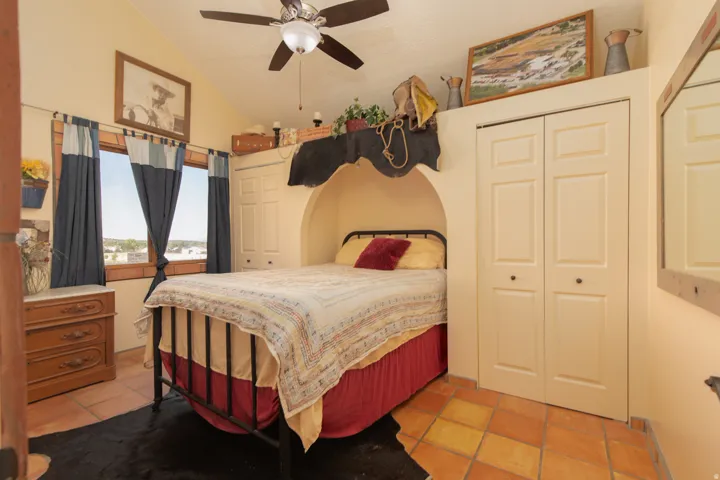 Bedroom featuring a ceiling fan, vaulted ceiling, light tile patterned floors, and a closet
