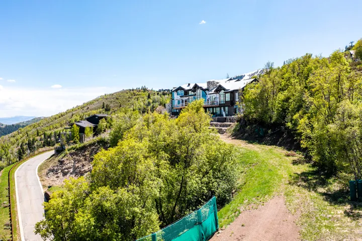 Hillside property featuring multi-level architecture with extensive glazing, stone accents, and a prominent deck