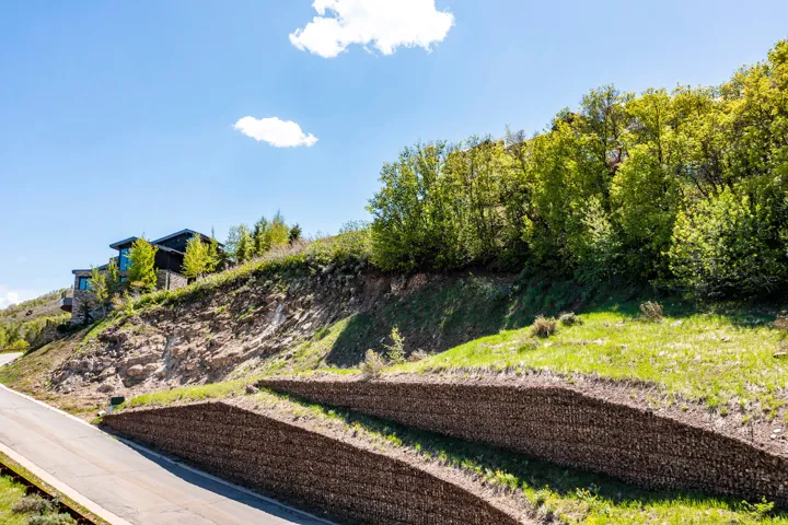 Modern architectural residence situated on a sloped hillside, featuring dark siding and expansive windows