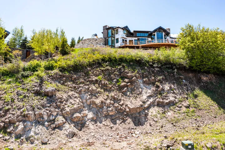 Hillside property featuring a multi-level structure with extensive decking, large windows, and a stone chimney