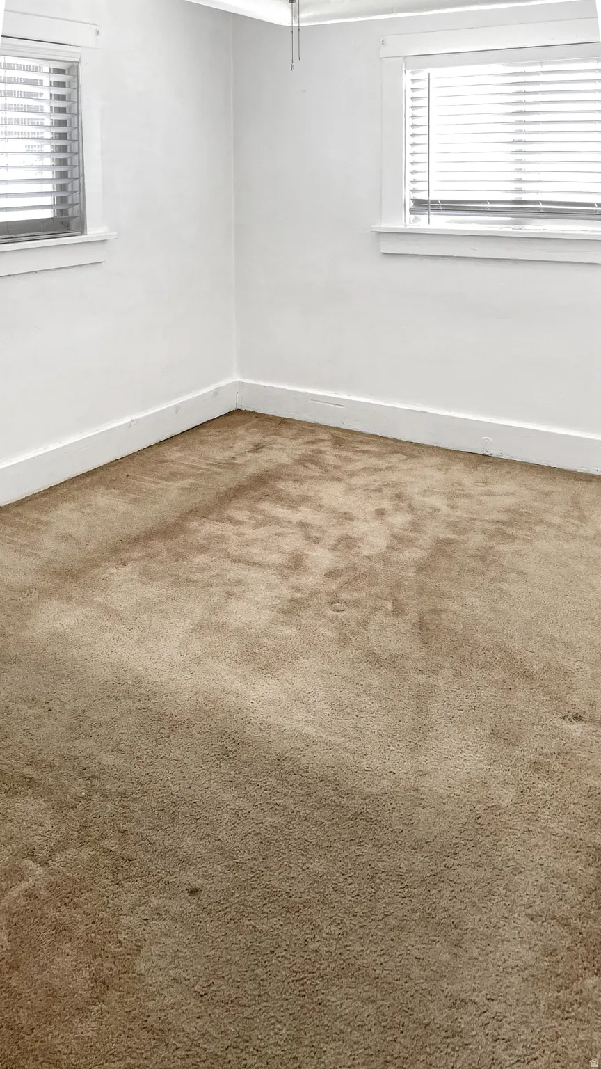 Empty room featuring light carpet and baseboards