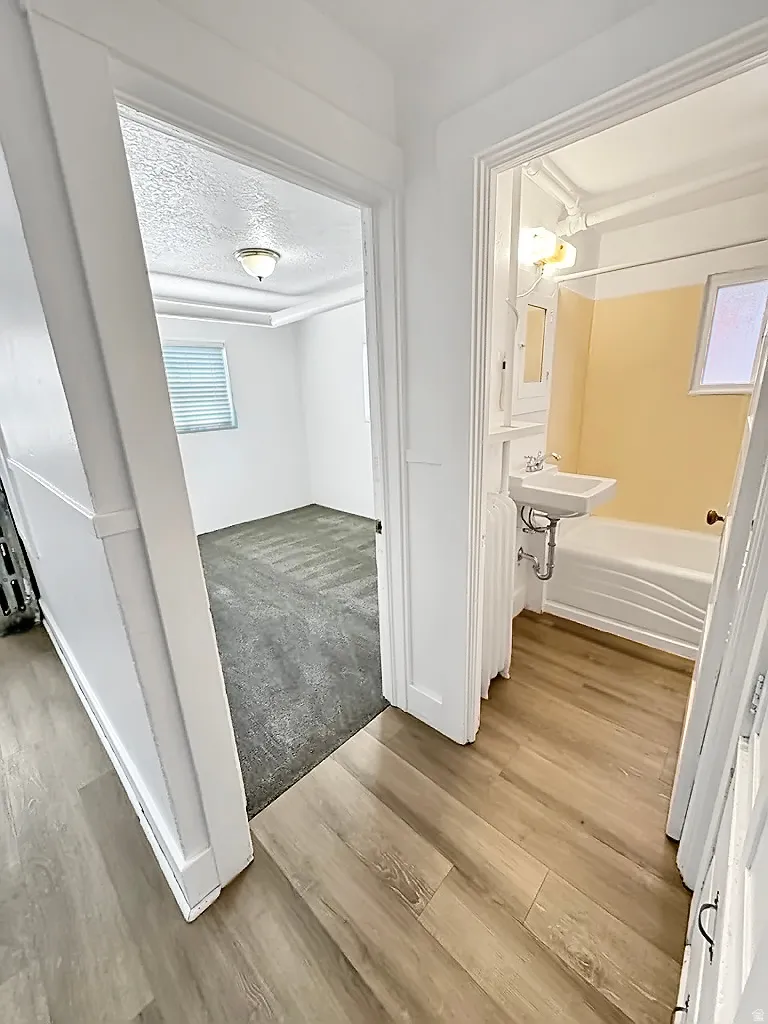 Corridor featuring light wood-style flooring and a textured ceiling