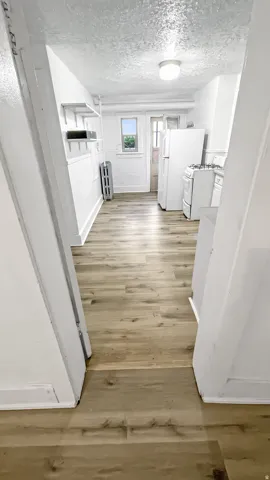 Hallway featuring light wood-type flooring, a textured ceiling, and radiator
