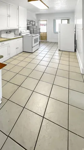Laundry area with light tile patterned floors, a textured ceiling, and water heater