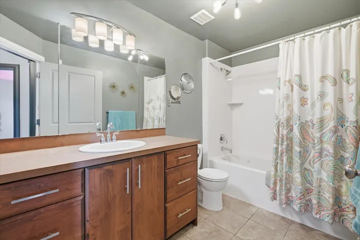 Full bathroom featuring vanity, shower / tub combo with curtain, and light tile patterned floors