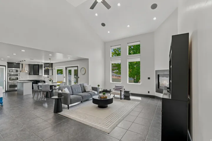 Vaulted ceilings highlight this open-concept living space, featuring large windows, a built-in fireplace, and tile flooring