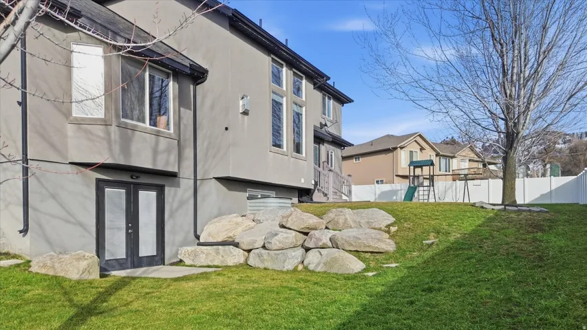 Back of house with stucco siding, a playground, and french doors