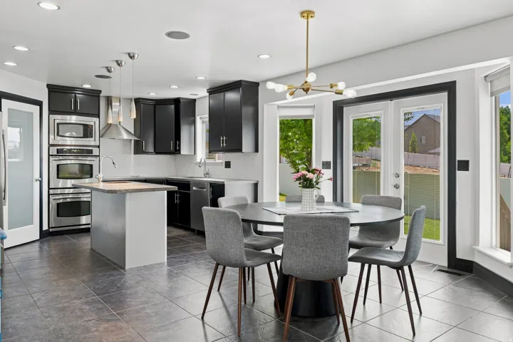 Open-concept kitchen featuring dark wood cabinetry, stainless steel appliances, a center island with a light-colored countertop, and slate-finish tile flooring