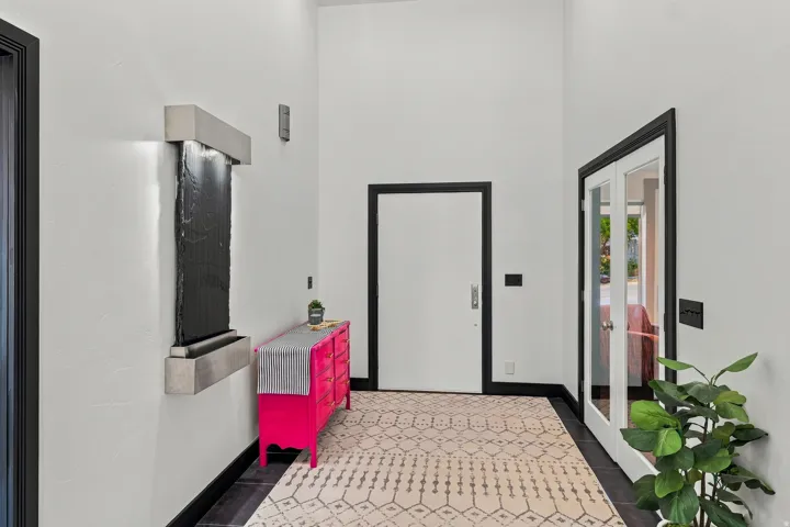 Modern entryway showcasing a geometric brick-pattern floor in neutral tones, crisp white walls, and black-framed architectural detailing