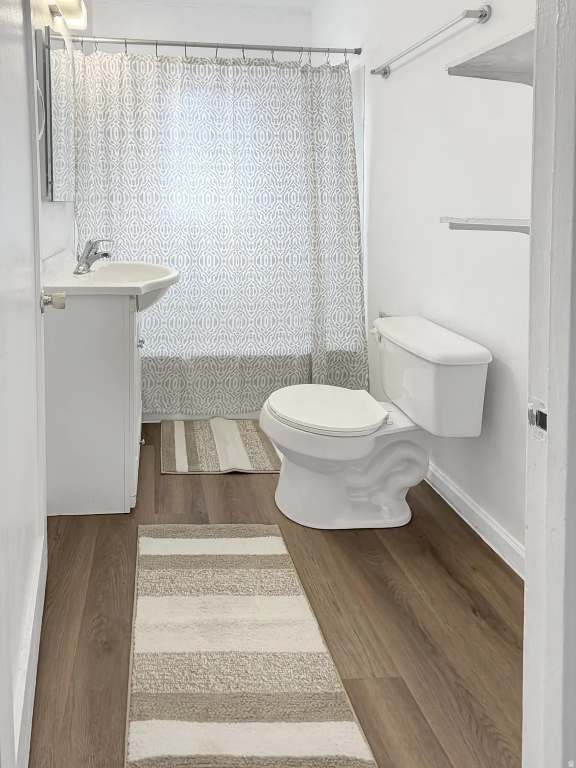 Bathroom featuring vanity, dark wood finished floors, and shower / bathtub combination with curtain