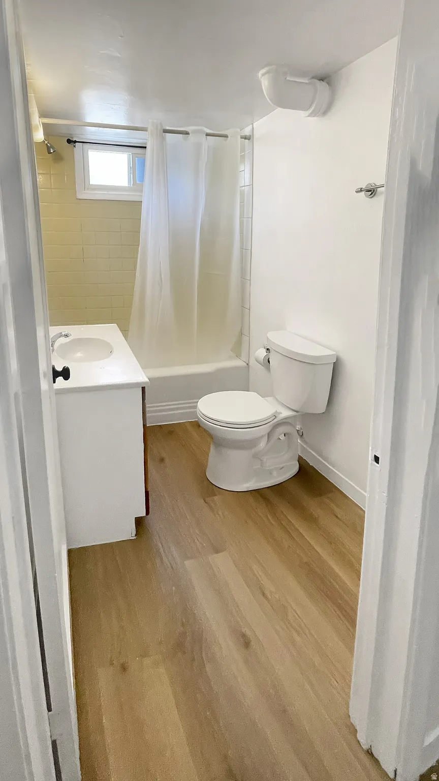 Full bath with vanity, shower / tub combo, and light wood-style floors
