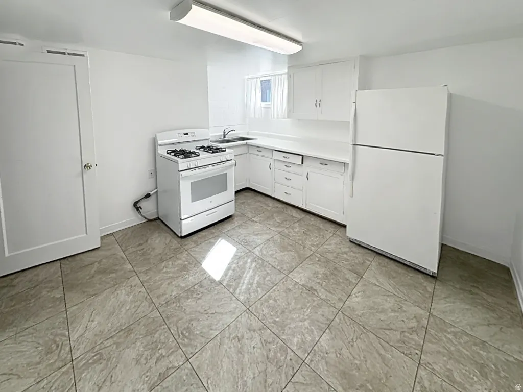 Kitchen featuring white appliances, white cabinets, and light countertops