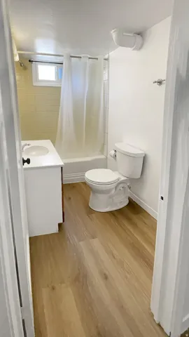 Full bath with vanity, shower / tub combo, and light wood-style floors