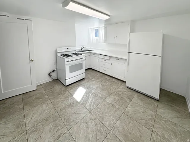 Kitchen featuring white appliances, white cabinets, and light countertops