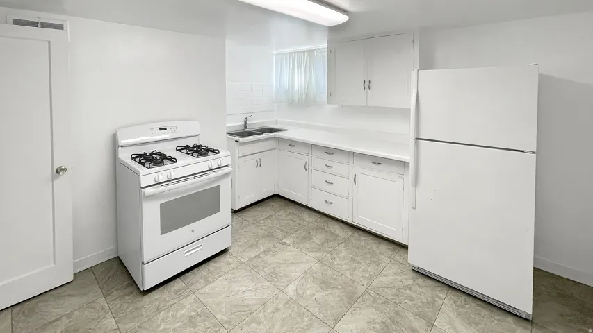 Kitchen featuring white appliances, white cabinetry, and light countertops