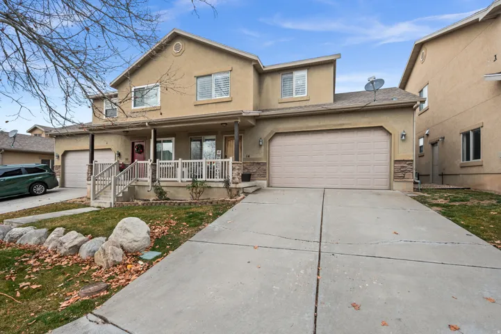 Traditional home featuring a porch, stucco siding, concrete driveway, and stone siding