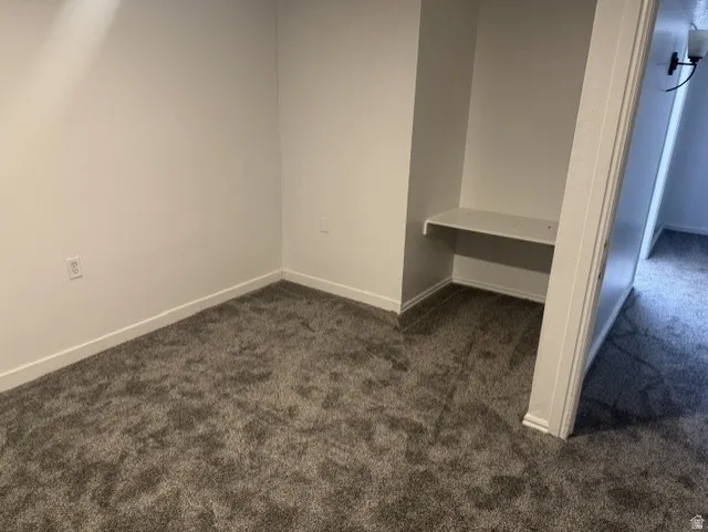 Plush gray carpeting throughout, featuring white baseboards and a built-in shelving nook