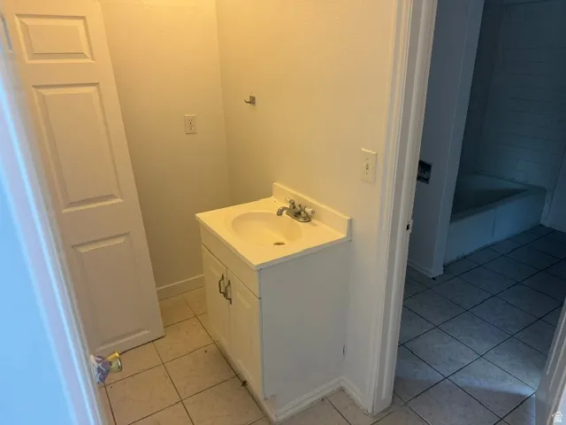 Single vanity with an integrated sink and base cabinet, set upon square tile flooring