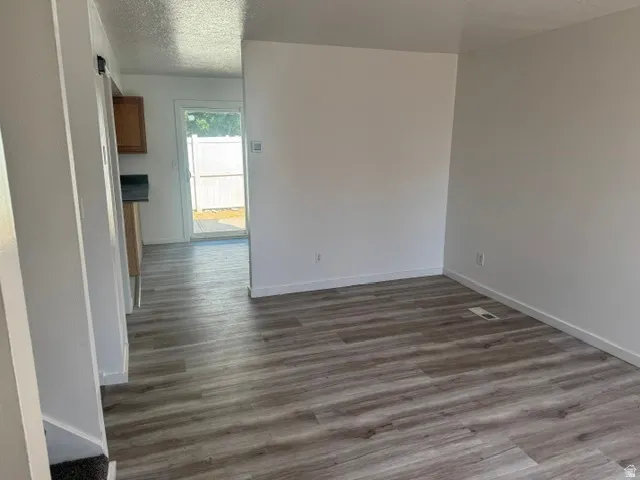 Spacious room with wood-finish flooring and crisp white walls