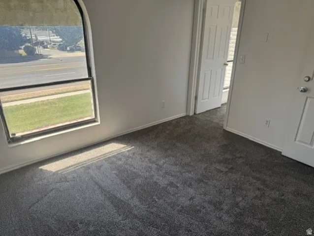 Interior space featuring new dark gray carpeting, light-colored walls, and white baseboards