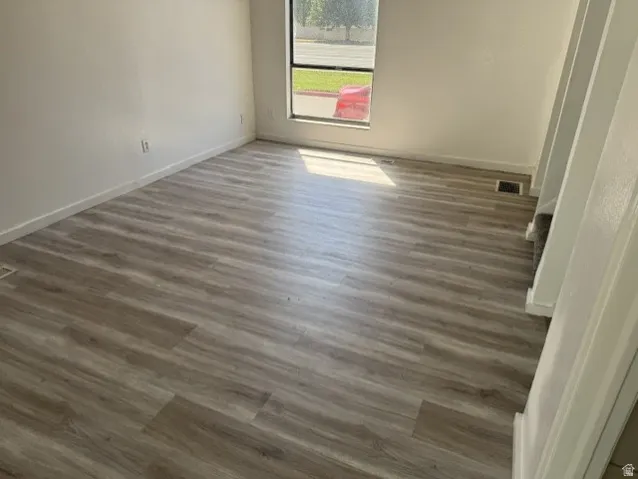 Wood-finish flooring with baseboards and natural light from a window
