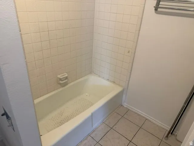 Bathtub featuring white ceramic subway tile surround and an integrated soap dish