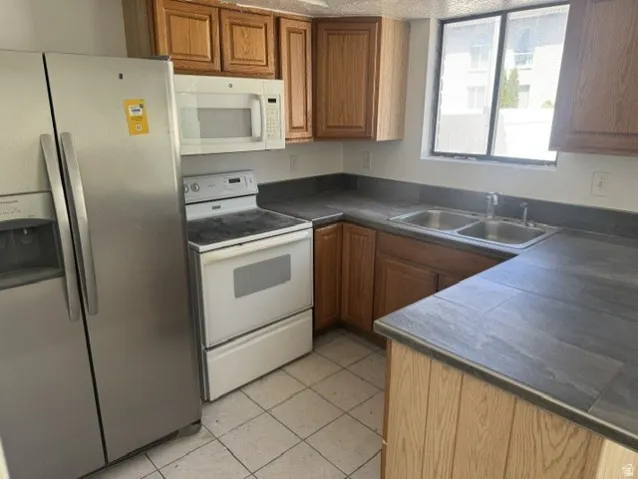 Kitchen featuring wood cabinetry, stone-look countertops, a double basin stainless steel sink, and a window above