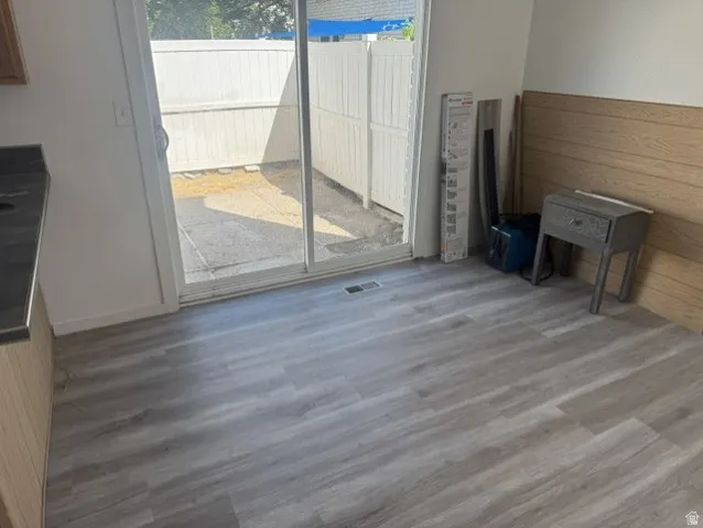 Newly installed wood-finish flooring throughout, featuring a sliding glass door providing access to a private outdoor patio space