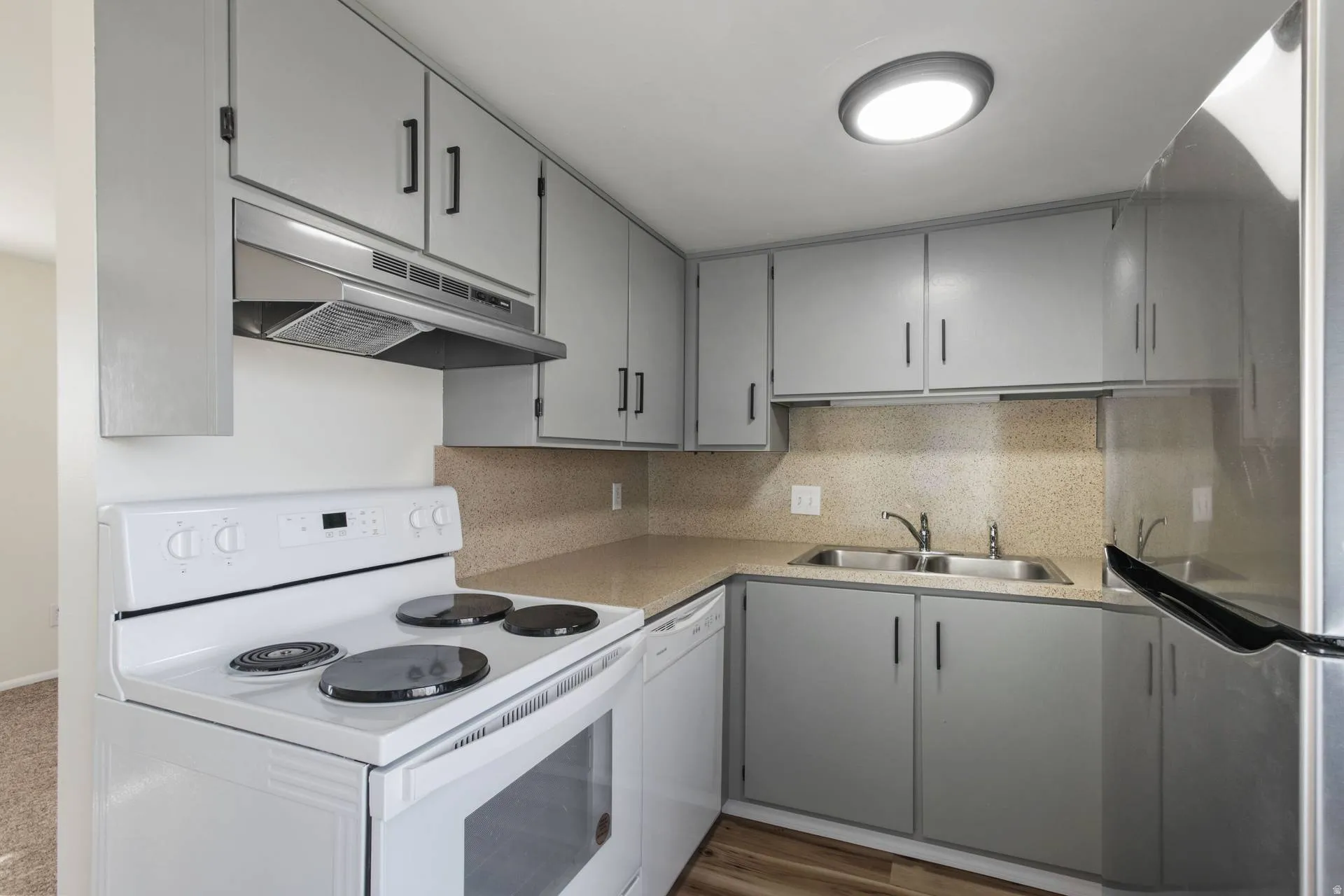 Kitchen featuring white appliances, gray cabinetry, tasteful backsplash, and light countertops