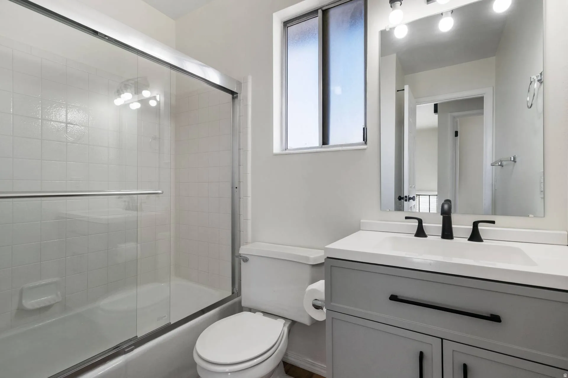 Bathroom with bath / shower combo with glass door and vanity