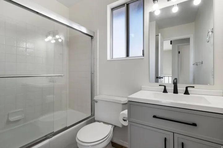 Bathroom with bath / shower combo with glass door and vanity