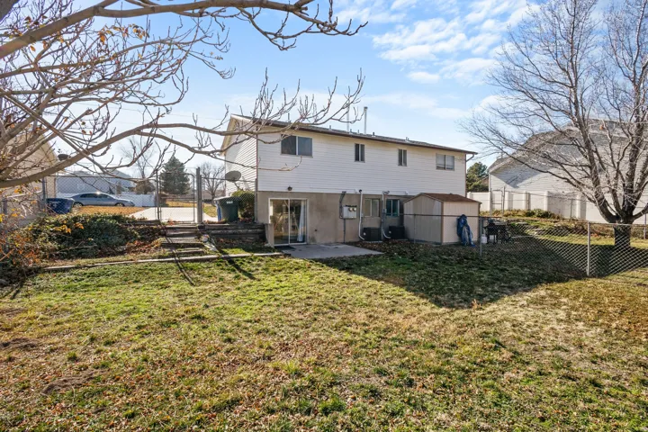 Back of property with a patio, a fenced backyard, and a storage shed