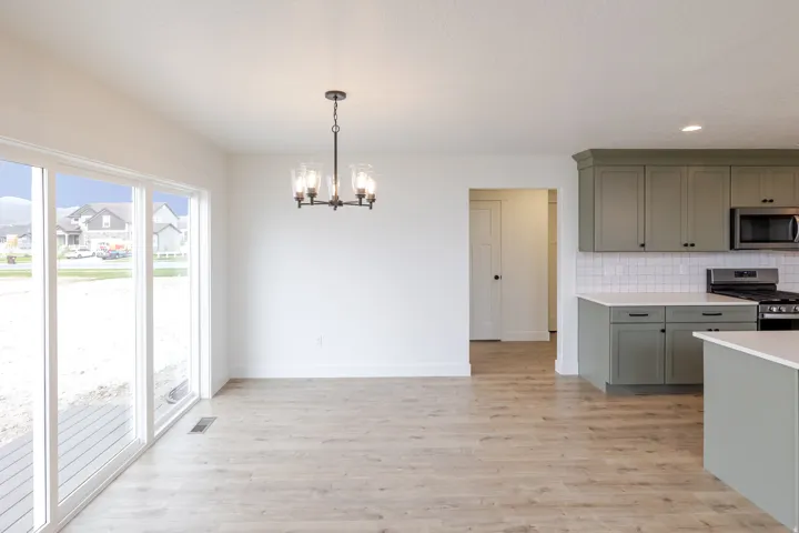 Open-concept living space featuring wood-finish flooring, a contemporary chandelier, and large sliding glass doors
