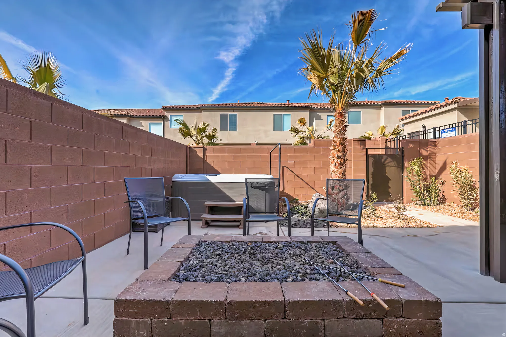 Fenced backyard featuring a hot tub, a patio area, and an outdoor fire pit