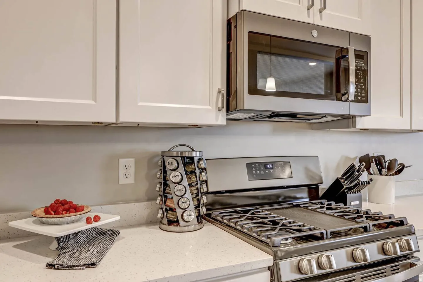 Kitchen view of stainless steel appliances, light stone countertops, and white cabinets