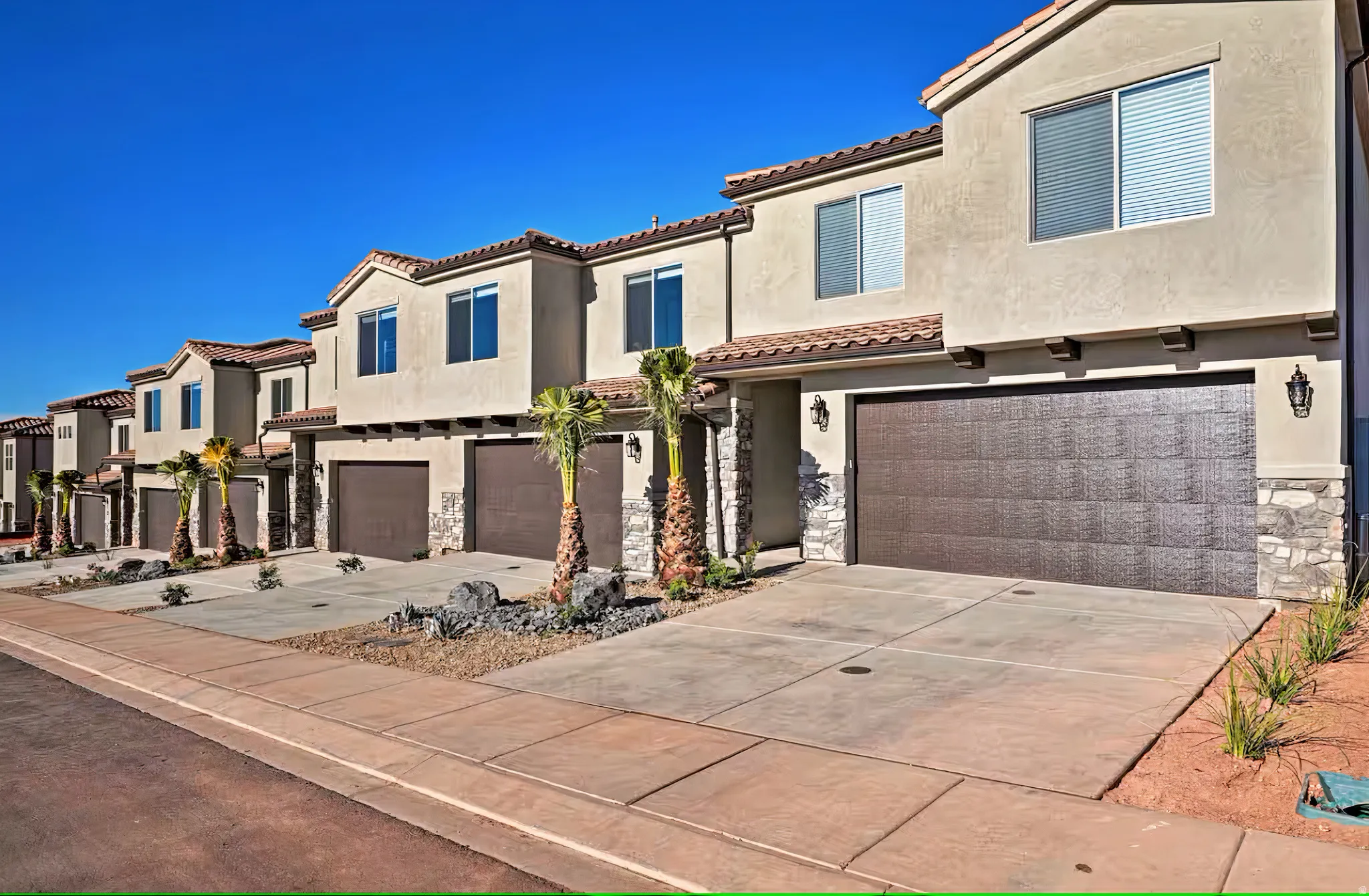 Mediterranean / spanish house with a garage, stone siding, driveway, stucco siding, and a residential view
